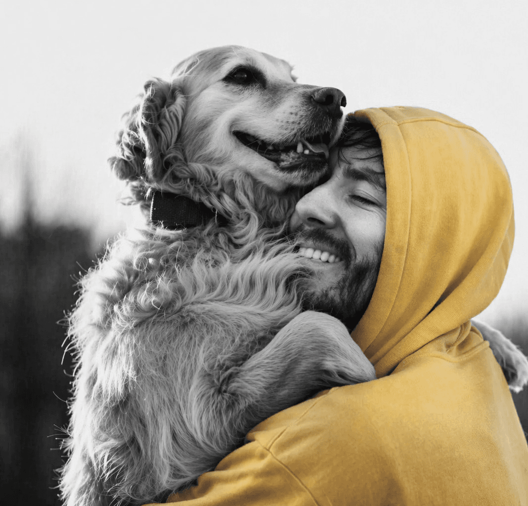 Person in yellow hoodie hugging a golden retriever